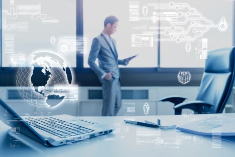 blur business man standing at window using tablet behind working desk